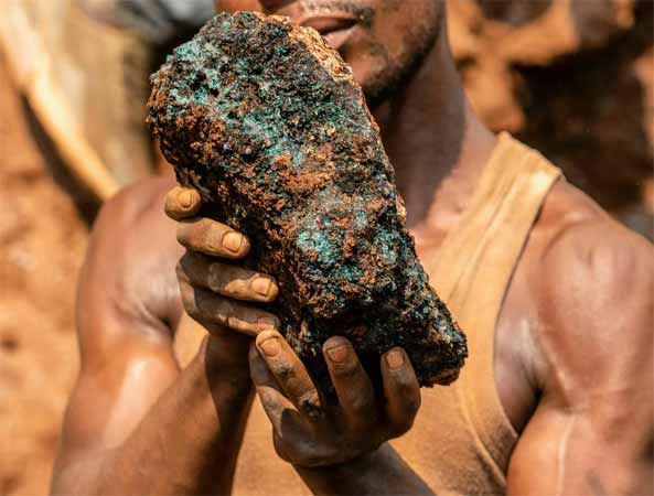 An artisanal miner holds a cobalt stone at the Shabara artisanal mine in the DRC.