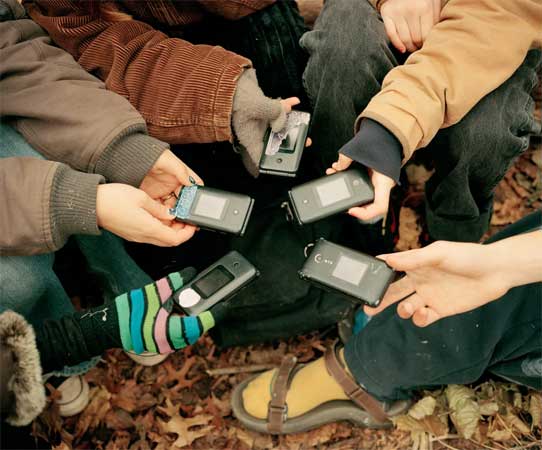 Luddite teens hold their vintage flip phones in a circle. 