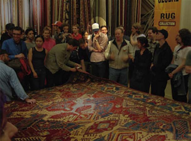 Capture of the Macy's 'love rug' flash mob, with organizers and many participants examining the rug in question.