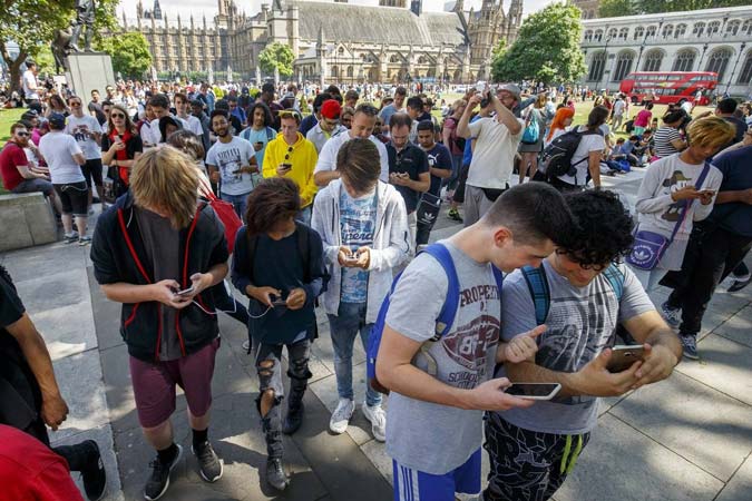 A densely packed crowd of young people look at their phones to capture Pokémon in a hotspot in the UK.